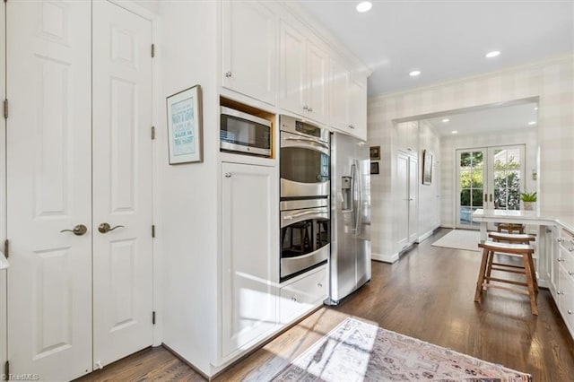 kitchen featuring french doors, stainless steel appliances, crown molding, dark hardwood / wood-style floors, and white cabinetry