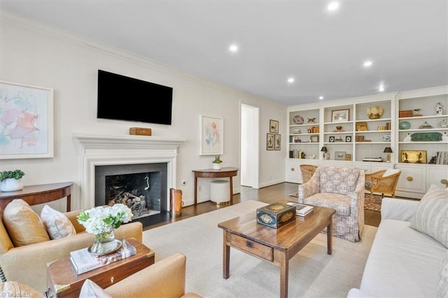 living room with wood-type flooring, built in features, and ornamental molding