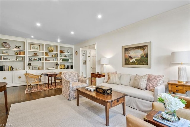 living room featuring built in shelves, dark hardwood / wood-style flooring, and crown molding