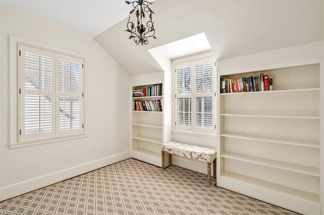 unfurnished room featuring built in shelves, vaulted ceiling, and a chandelier