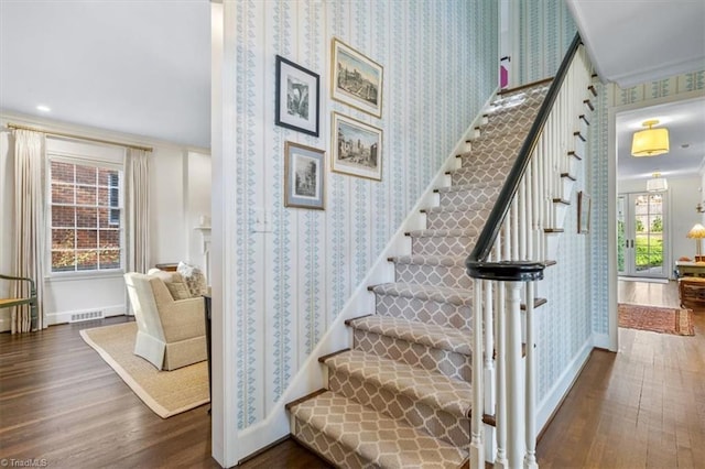 staircase with wood-type flooring and ornamental molding