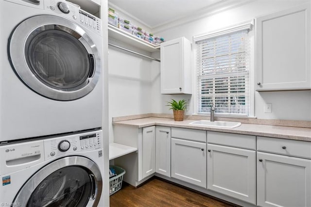 clothes washing area featuring cabinets, crown molding, sink, dark hardwood / wood-style floors, and stacked washer / dryer