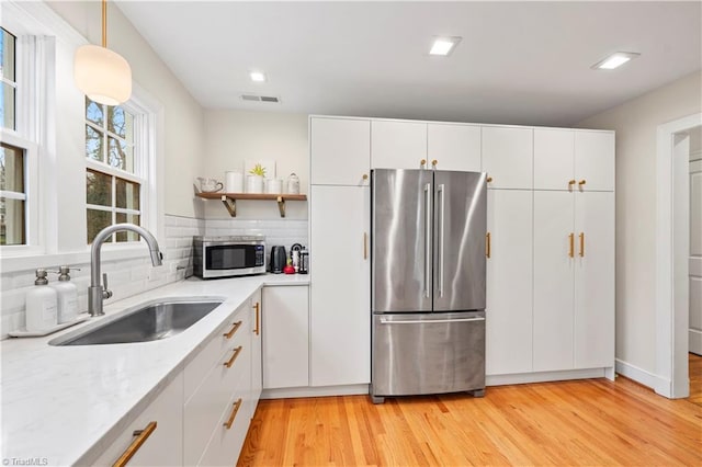 kitchen with white cabinets, stainless steel appliances, tasteful backsplash, and sink