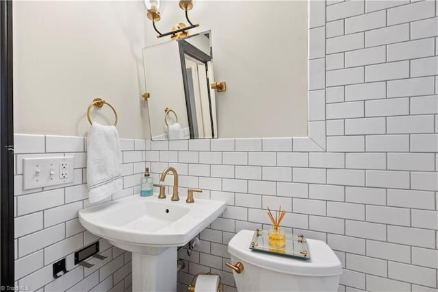 bathroom with backsplash, toilet, tile walls, and sink