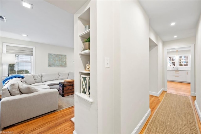 hall with built in shelves and light hardwood / wood-style floors