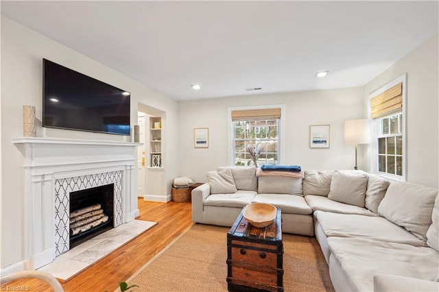 living room featuring a fireplace, light hardwood / wood-style floors, and built in features