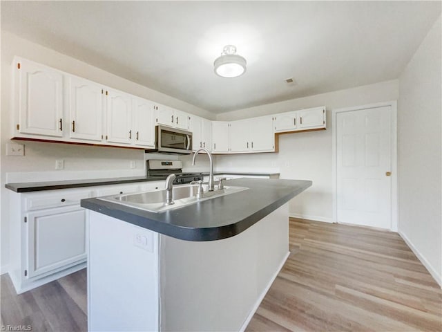 kitchen with white cabinets, stainless steel appliances, and light wood-type flooring