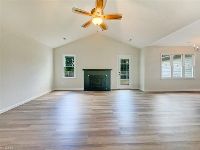 unfurnished living room featuring ceiling fan with notable chandelier, light wood-type flooring, and lofted ceiling