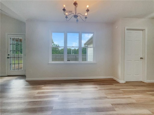 unfurnished dining area featuring a notable chandelier and light wood-type flooring