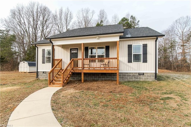 view of front of home with a porch, a front lawn, and a shed