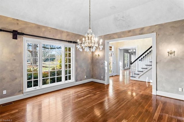 unfurnished dining area with wood-type flooring and an inviting chandelier