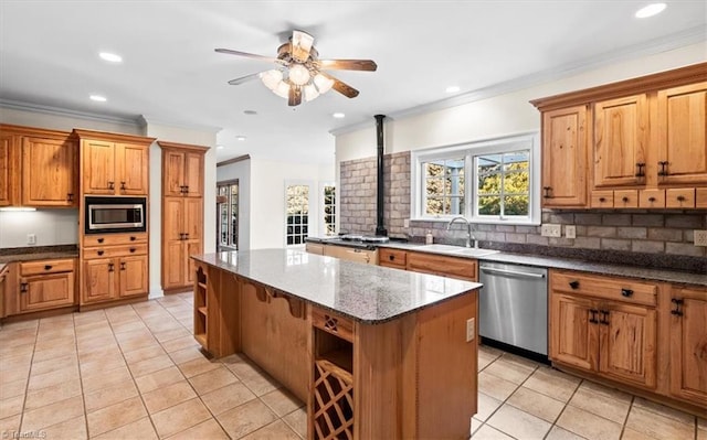 kitchen featuring a kitchen island, stone counters, appliances with stainless steel finishes, ornamental molding, and sink