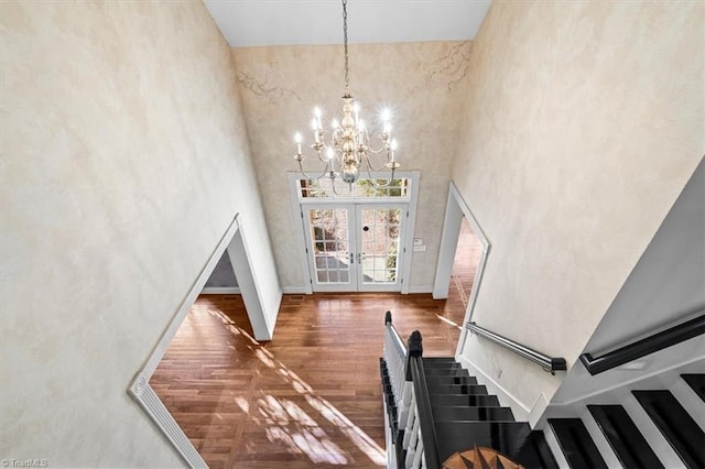 stairs with a towering ceiling, french doors, and a chandelier