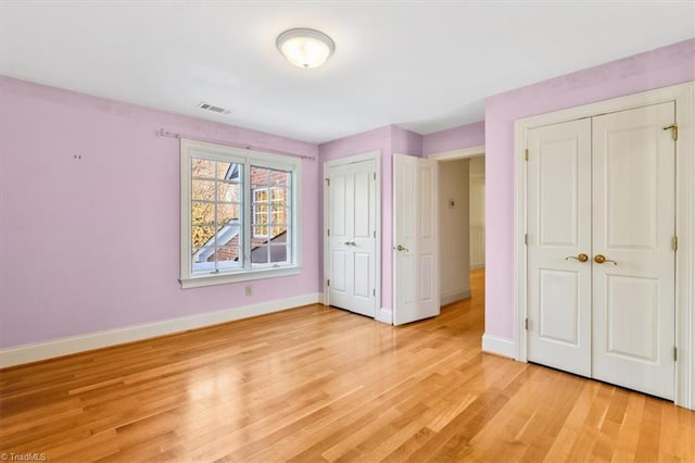 unfurnished bedroom with multiple closets and light hardwood / wood-style floors