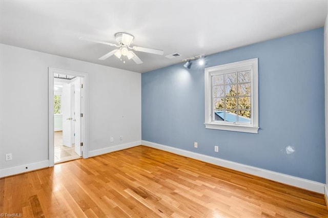 unfurnished room with a healthy amount of sunlight, ceiling fan, light hardwood / wood-style flooring, and track lighting