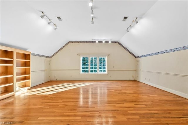 additional living space featuring lofted ceiling and light hardwood / wood-style flooring