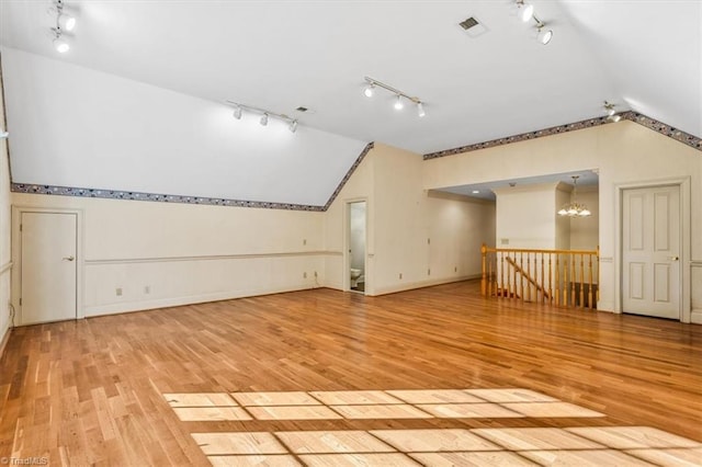 additional living space featuring light hardwood / wood-style floors, vaulted ceiling, and a chandelier