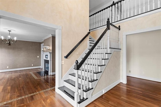 staircase featuring crown molding, a chandelier, and hardwood / wood-style flooring