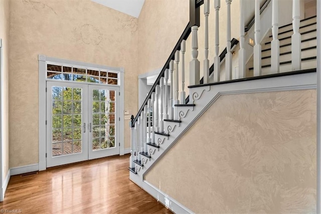 stairs featuring a high ceiling, hardwood / wood-style floors, and french doors