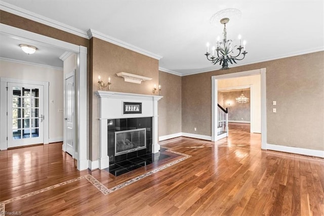 unfurnished living room with an inviting chandelier, a tile fireplace, crown molding, and hardwood / wood-style flooring