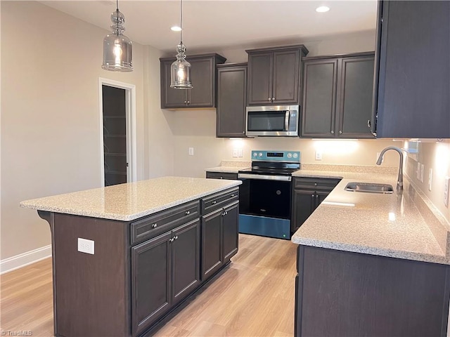 kitchen with stainless steel appliances, recessed lighting, hanging light fixtures, a sink, and light wood-type flooring