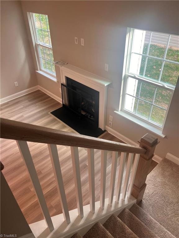 stairs featuring a fireplace, wood finished floors, and baseboards