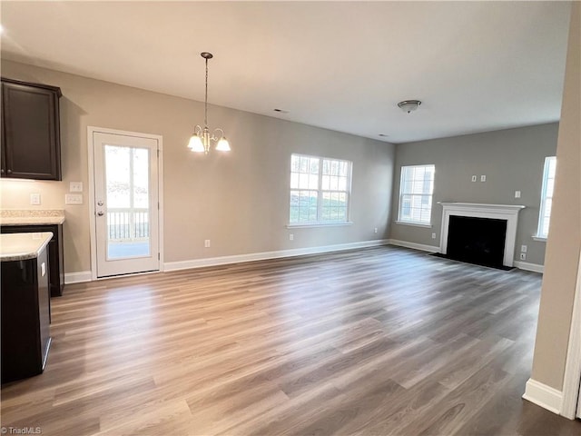 unfurnished living room with a fireplace with flush hearth, light wood-style floors, and baseboards