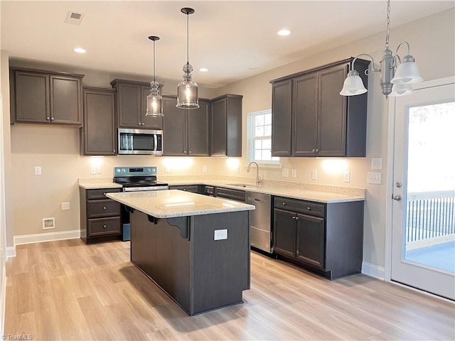 kitchen with light wood-style floors, stainless steel appliances, a sink, and a center island