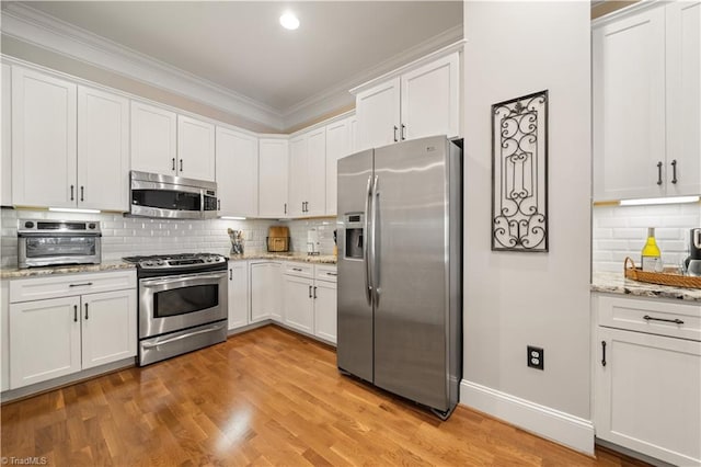 kitchen with stainless steel appliances, light wood-style flooring, white cabinets, and ornamental molding