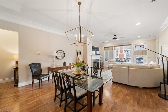 dining area with a fireplace, wood finished floors, and ornamental molding