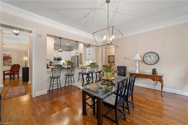 dining room with an inviting chandelier, crown molding, baseboards, and wood finished floors