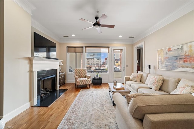 living room featuring crown molding, baseboards, light wood-type flooring, recessed lighting, and a fireplace