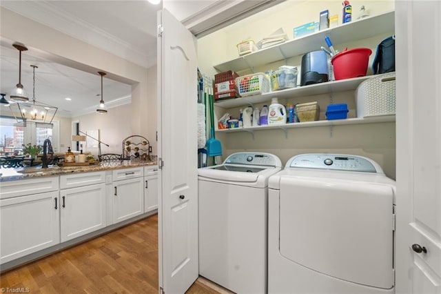 laundry room with light wood finished floors, crown molding, laundry area, washer and dryer, and a sink