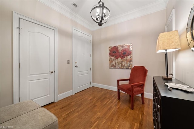 sitting room with light wood finished floors, visible vents, baseboards, a chandelier, and ornamental molding