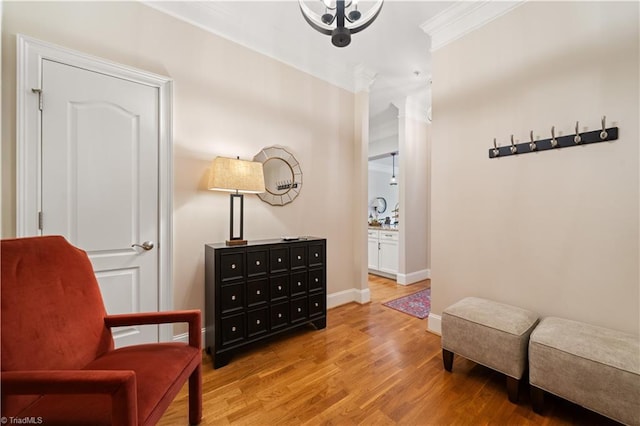 living area featuring light wood-type flooring, crown molding, and baseboards