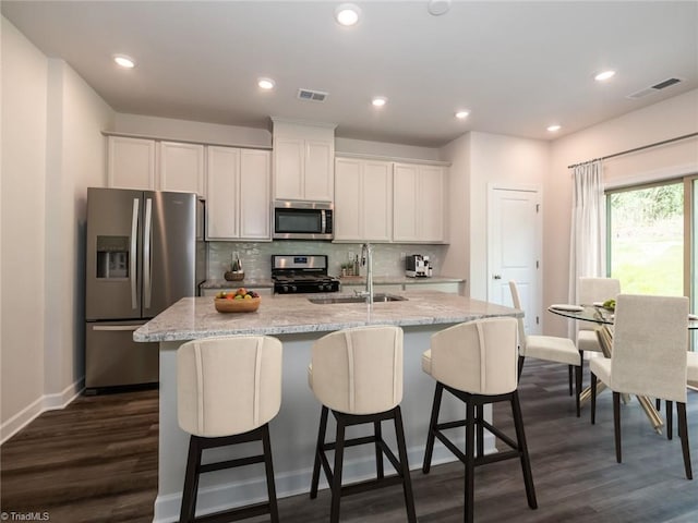 kitchen with white cabinetry, stainless steel appliances, dark hardwood / wood-style flooring, an island with sink, and sink