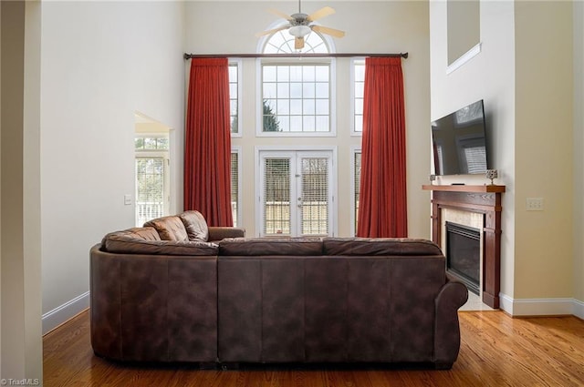 living room with ceiling fan, a towering ceiling, and hardwood / wood-style floors