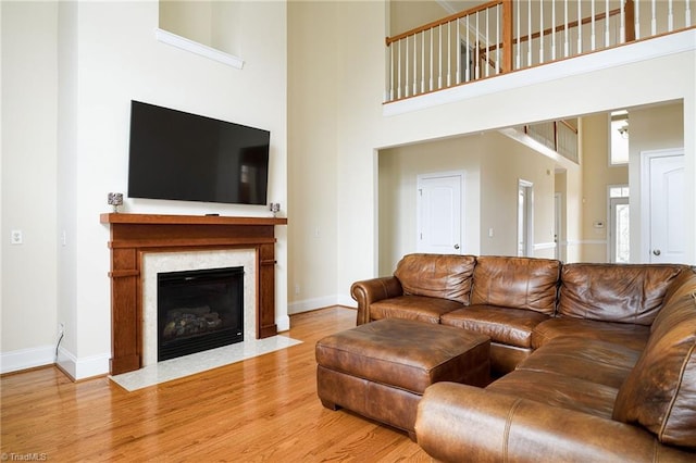 living room with hardwood / wood-style flooring, a premium fireplace, and a high ceiling