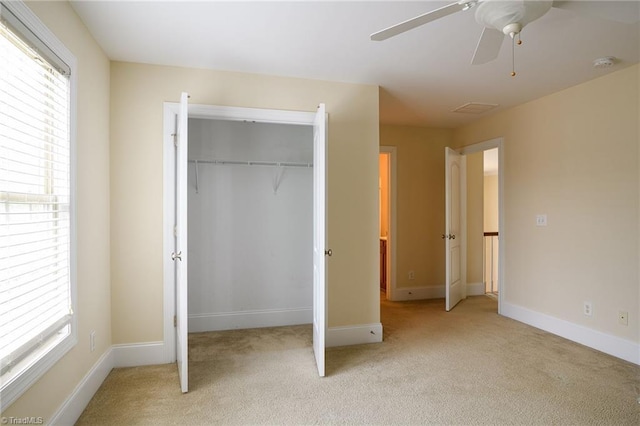 unfurnished bedroom with light carpet, a closet, and ceiling fan