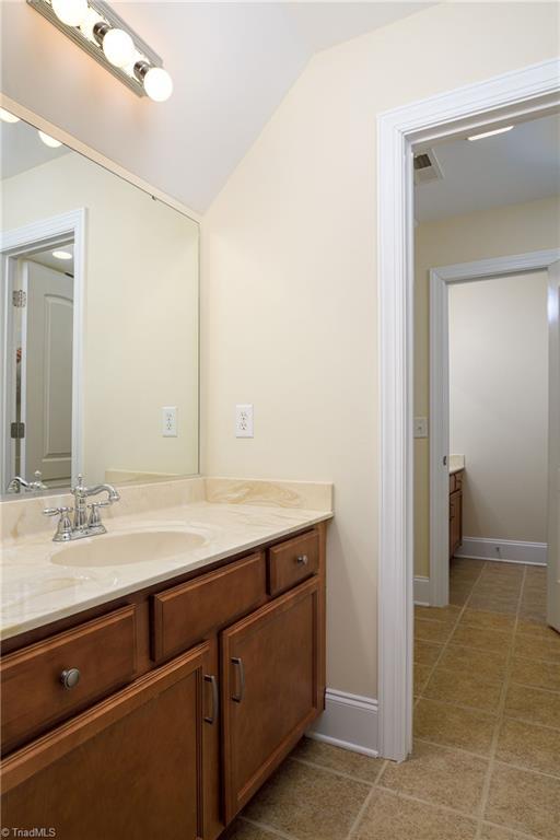 bathroom with vanity, lofted ceiling, and tile patterned floors