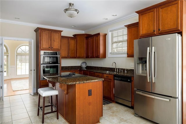 kitchen featuring a kitchen bar, sink, a center island, dark stone counters, and stainless steel appliances