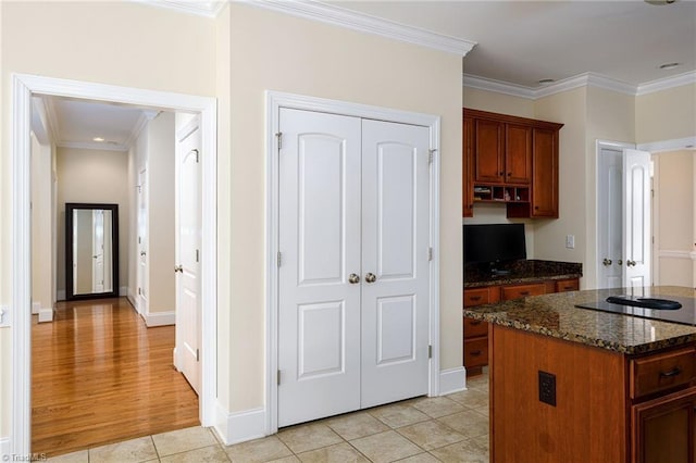 kitchen featuring light tile patterned flooring, a kitchen island, dark stone countertops, and crown molding