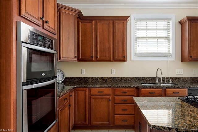 kitchen with stainless steel double oven, sink, and dark stone countertops