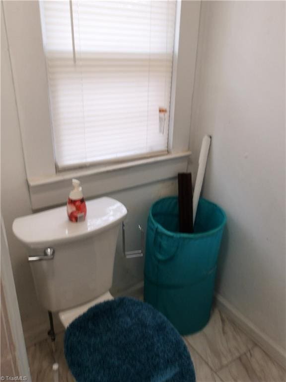 half bathroom featuring toilet and baseboards