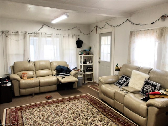 carpeted living area with beam ceiling