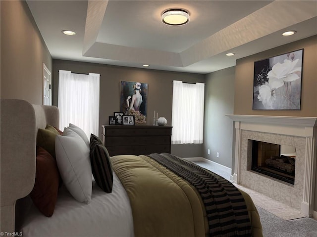 carpeted bedroom with recessed lighting, baseboards, a tile fireplace, and a tray ceiling