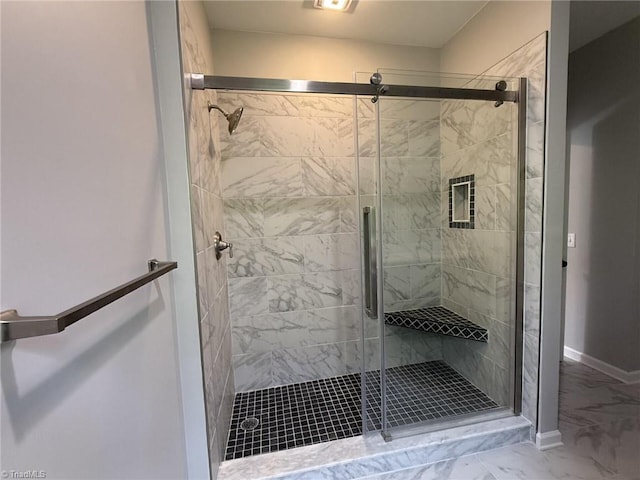 full bathroom featuring marble look tile flooring, a stall shower, and baseboards