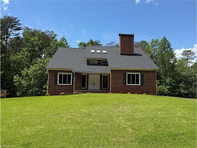 view of front of house featuring a chimney, a front yard, brick siding, and roof with shingles