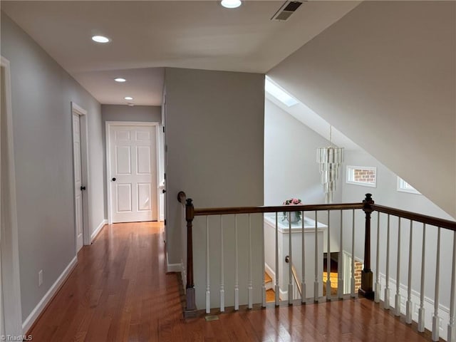 corridor with an upstairs landing, wood finished floors, recessed lighting, and baseboards