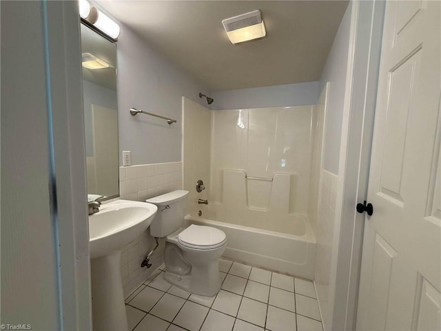 full bath with tile patterned flooring, tile walls, toilet, a wainscoted wall, and bathtub / shower combination